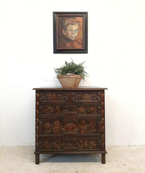 Antique portrait above an antique carved-wood chest of drawers.