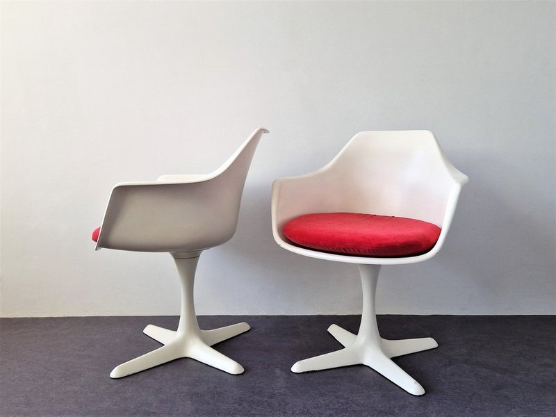 A pair of Tulip chairs with red cushioned seats. 