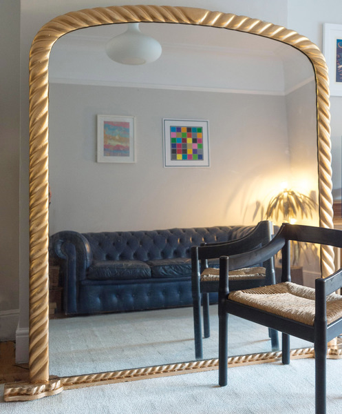 A large, braided-frame gold mirror in a living room