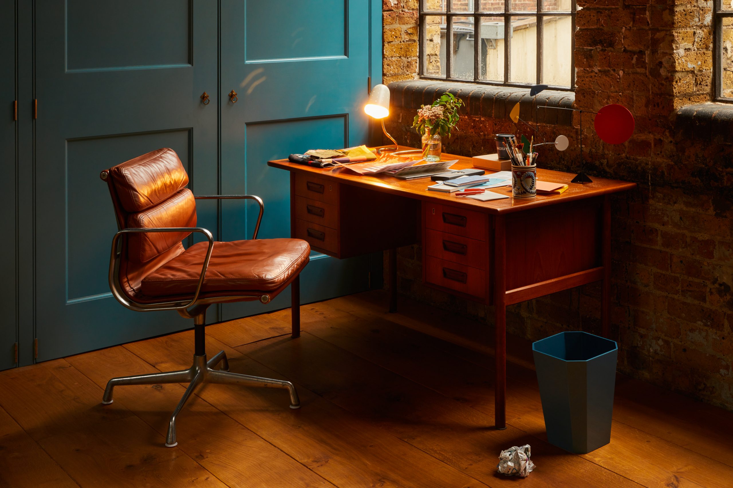 A mid-century desk and chair with a small task lamp on top.