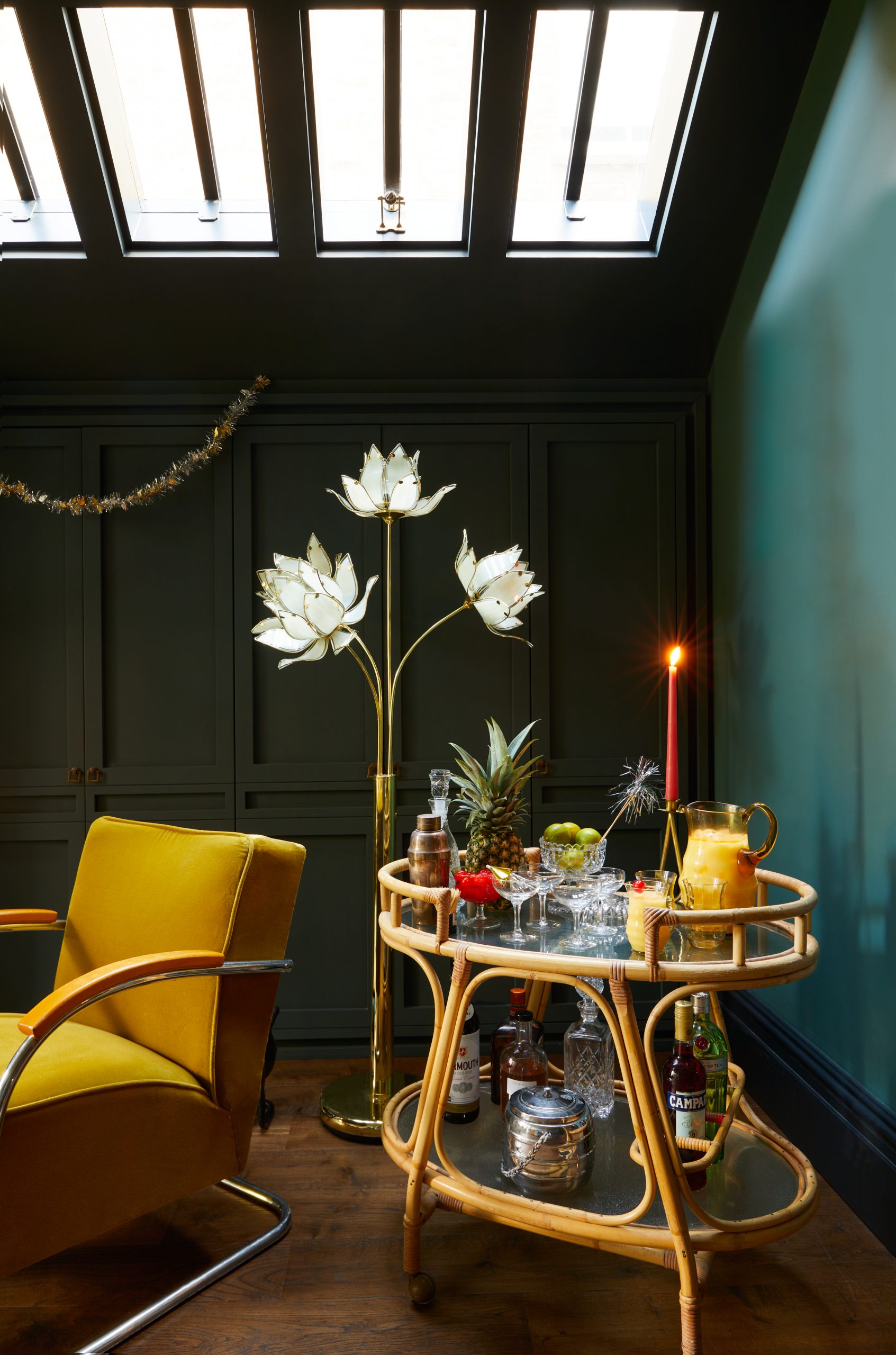 A bar trolley set up next to a sculptural floor lamp