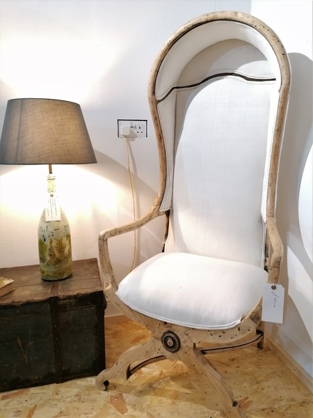 A linen upholstered Porter's chair next to a decorative lamp.