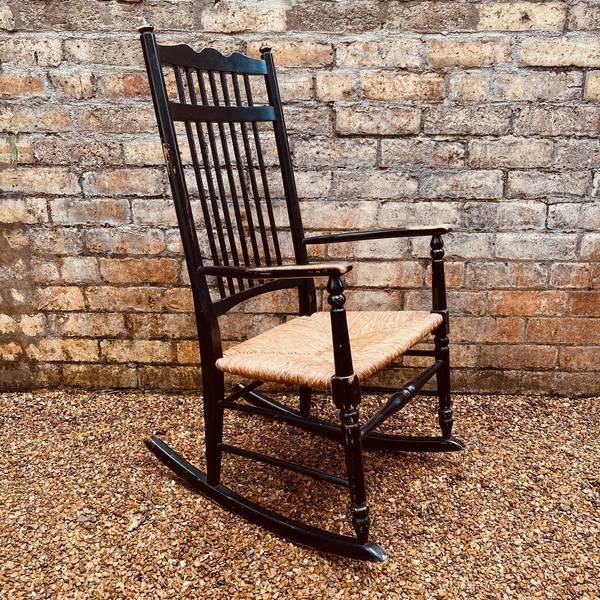 A Sussex rocking chair with an enonised wood frame set on a gravel patio