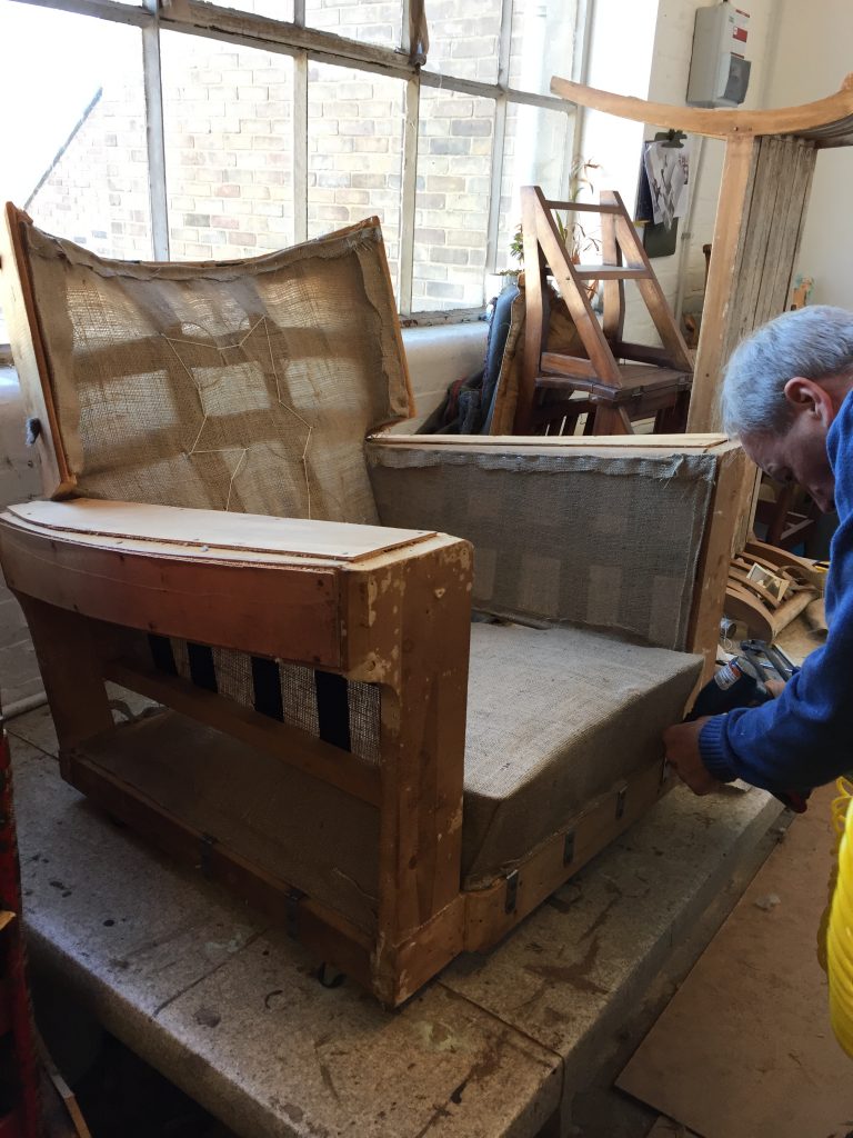 A chair stripped back to its shell and ready for reupholstering.